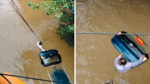 Man Stands in Rising Floodwaters to Protect Car